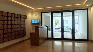 A reception area with a wall-mounted storage unit, a television, and a sliding glass door leading outside.