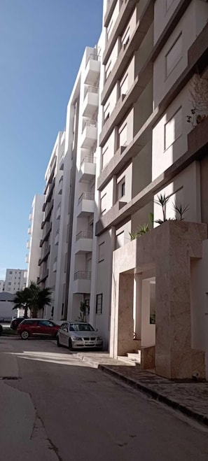 A multi-story residential building with balconies, a driveway, and parked cars. - Imavac Appartements (Tunis)