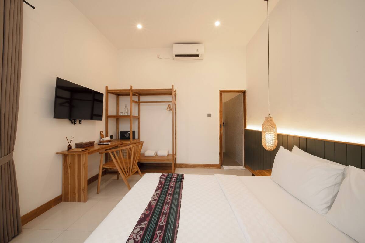 Une chambre à coucher comprenant un lit, une télévision, un bureau, une armoire et un climatiseur.