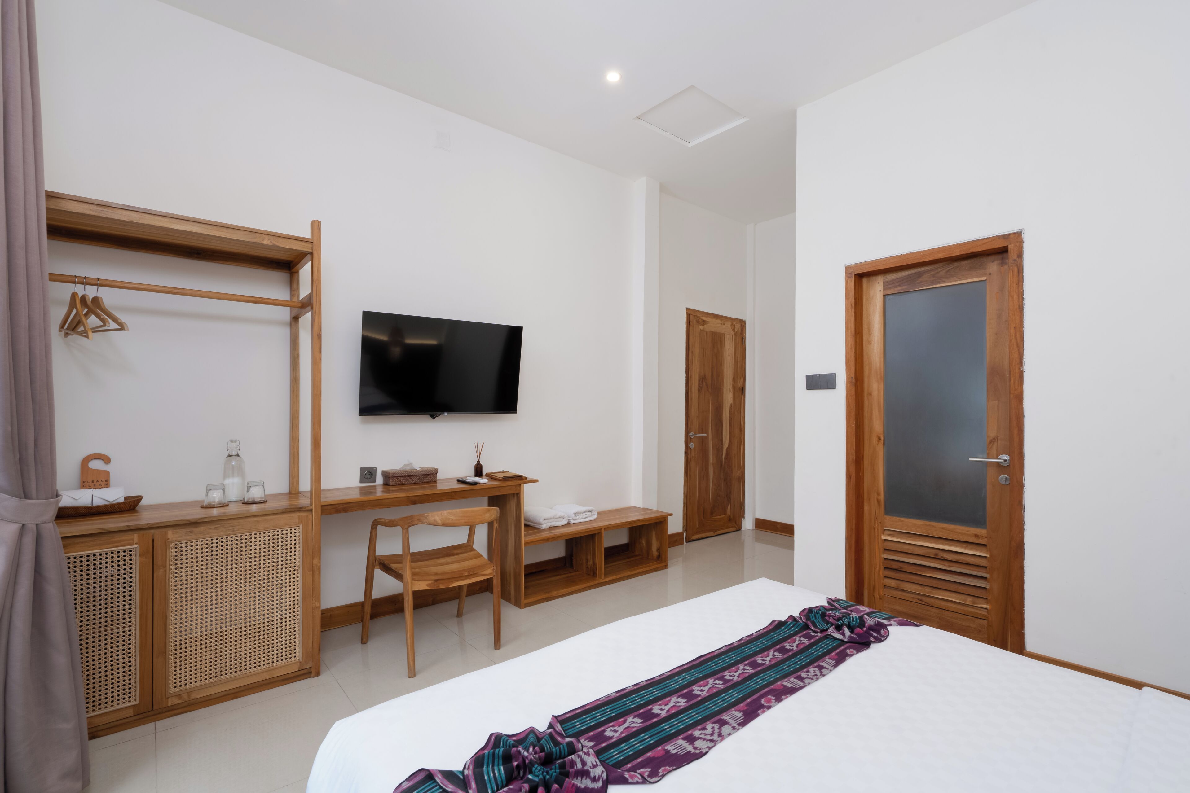Camera da letto con un letto, una TV, una scrivania, una sedia, un armadio e una porta.