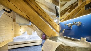 Une cabane en bois avec un lit superposé, un lavabo en pierre et un plafond en bois.