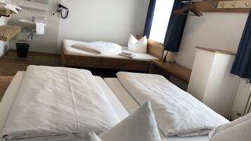Une chambre d’hôtel avec deux lits, un plancher en bois, un lavabo et un miroir.