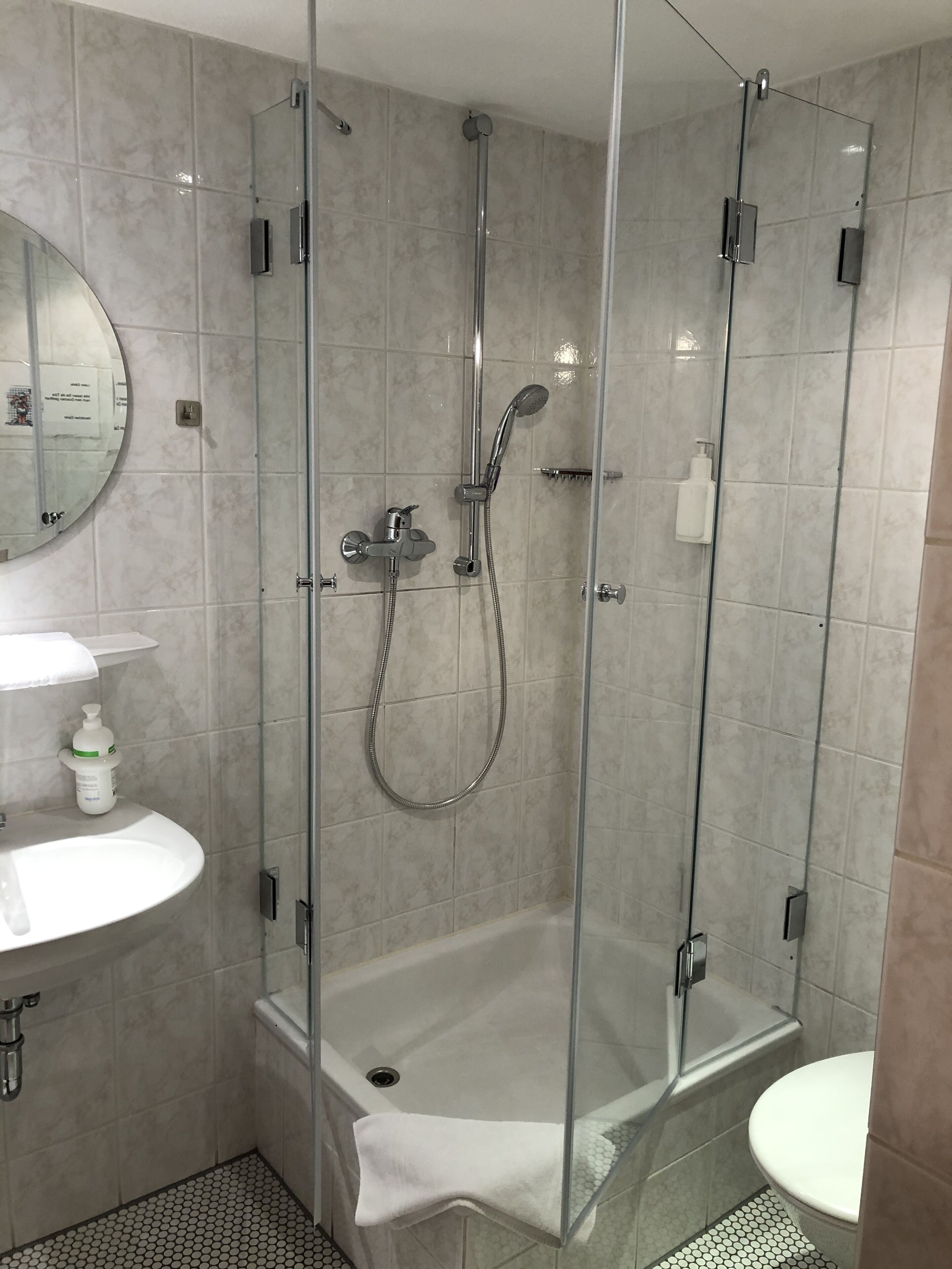 Une salle de bain moderne avec une douche à parois de verre, un lavabo blanc et des toilettes.
