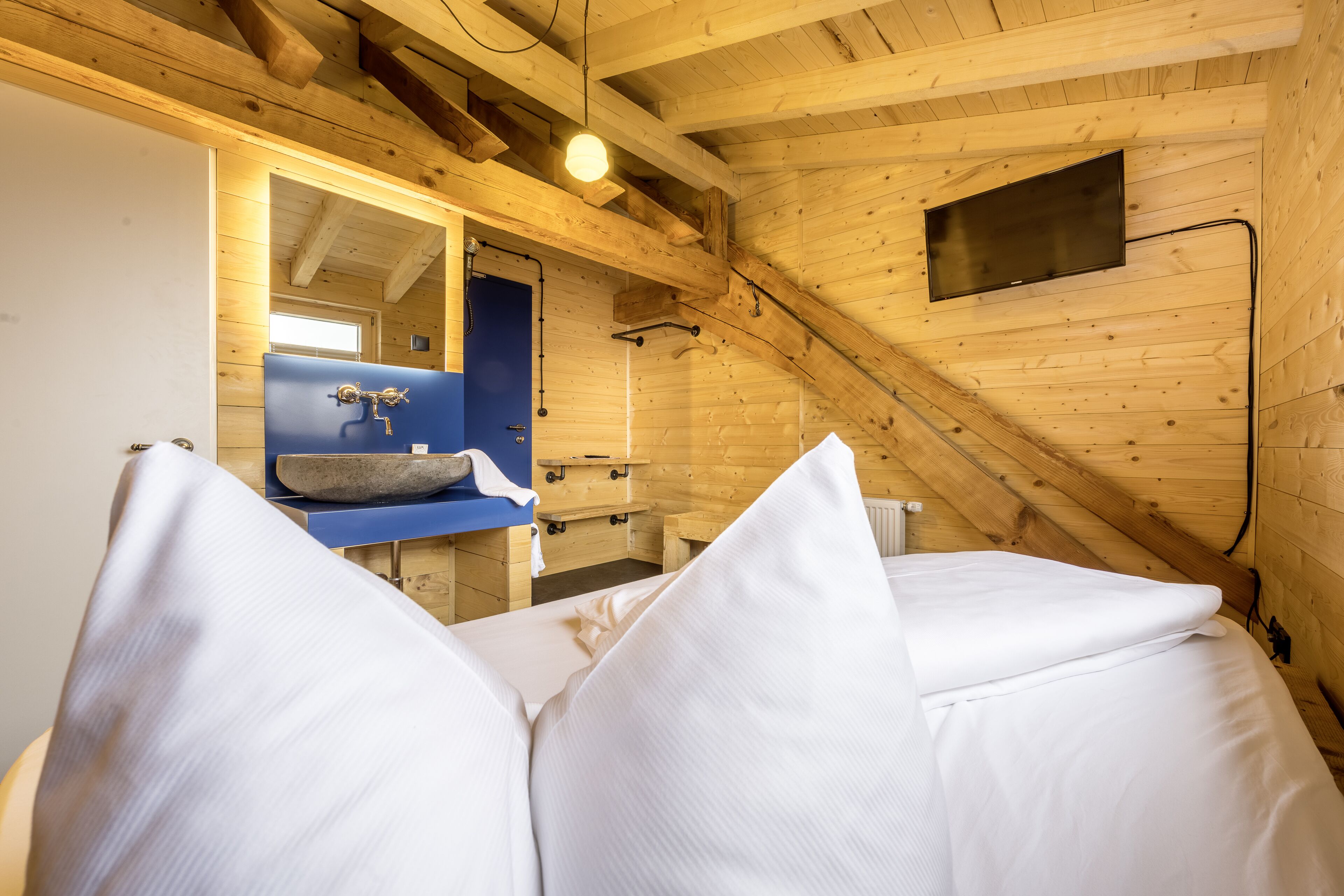 A wooden interior with a bed, a sink, and a mirror.