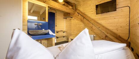 A wooden interior with a bed, a sink, and a mirror.