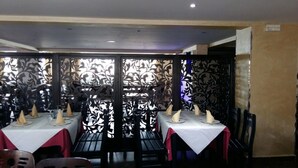A restaurant with tables set for dining, featuring a decorative partition with intricate patterns. - Hôtel Marina (Tetouan)