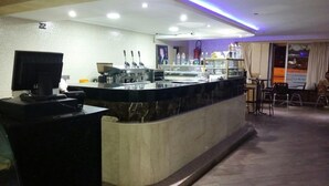 A hotel reception area with a marble counter, a television, and a seating area with chairs. - Hôtel Marina (Tetouan)