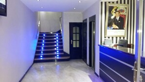 A hotel lobby with a staircase, reception desk, and a framed picture on the wall. - Hôtel Marina (Tetouan)