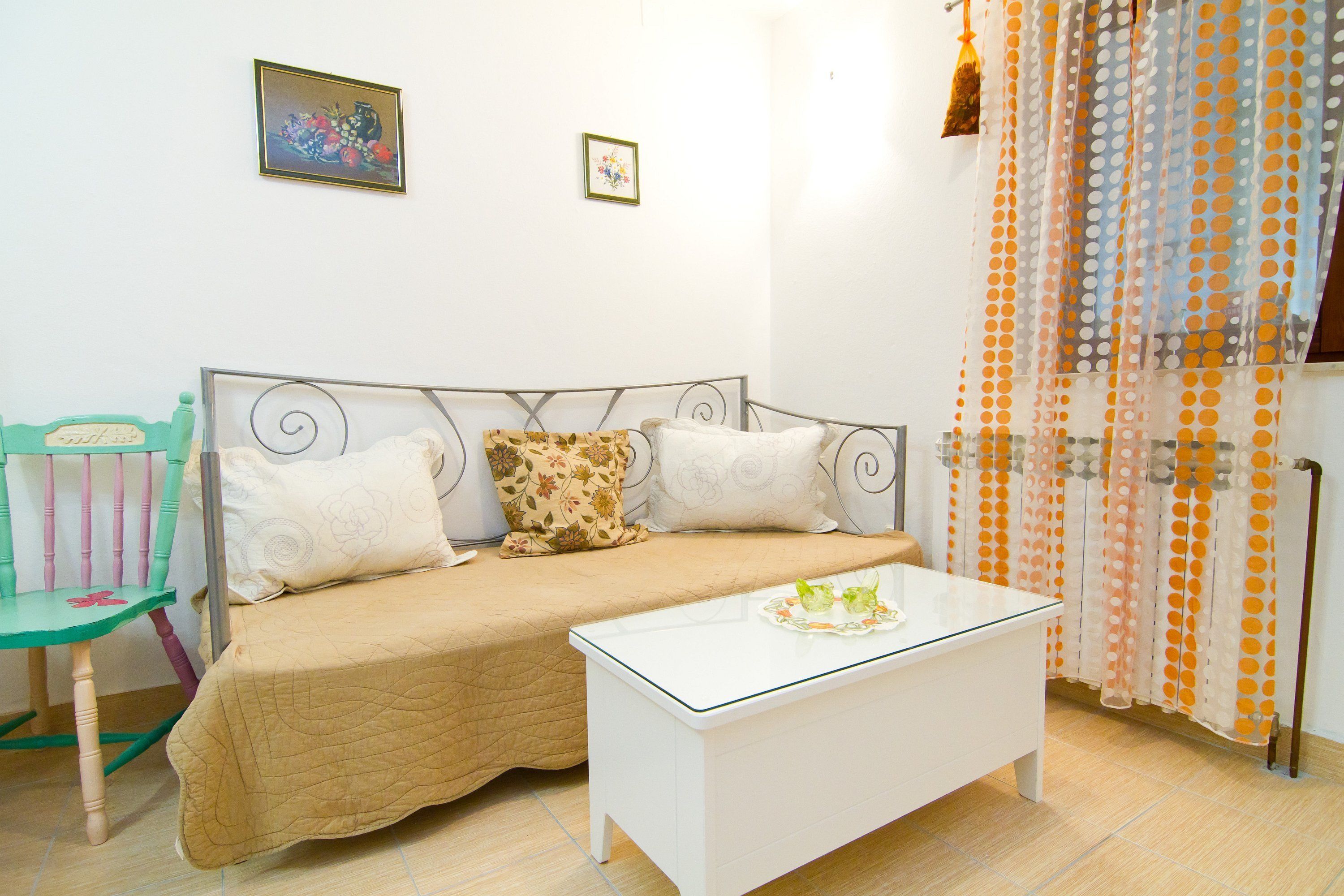 A bedroom with a bed, a chair, a bedside table, and a curtain.