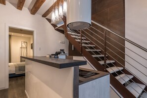 A modern kitchen with a built-in island, stainless steel appliances, and a staircase with a metal railing. - La Loggia della Luna (Venice)