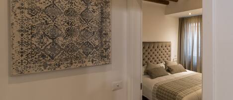 Un dormitorio con cabecera capitonada, una obra de arte grande con estampado en la pared y una cama con edredón estampado.