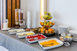 Una mesa de bufé con diversos alimentos y utensilios de servicio.