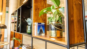 A modern interior with wooden shelves, a potted plant, and a book titled "La arquitectura". - Hotel HC Mollet Barcelona (Mollet del Valles)