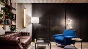 A modern living room with a leather sofa, a blue armchair, a coffee table, and a floor lamp. - Hotel HC Mollet Barcelona (Mollet del Valles)