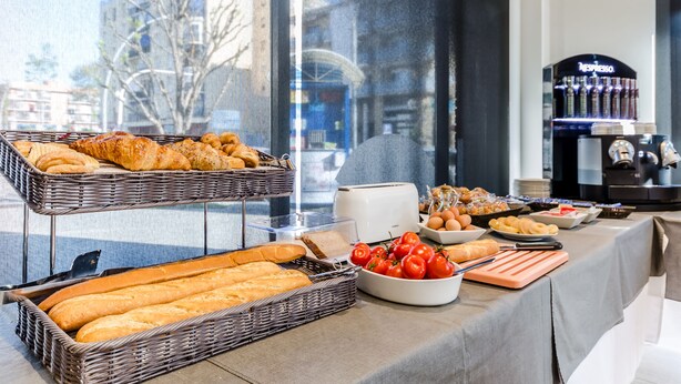 A buffet table with bread, tomatoes, and a coffee machine. - Hotel HC Mollet Barcelona (Mollet del Valles)