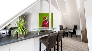 A modern kitchen with a glass countertop, a potted plant, and a painting of a dog. - Postsattler City Apartments (Albstadt)