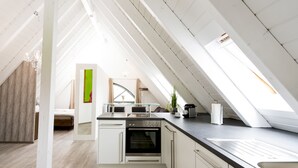 A modern kitchen with a skylight, white cabinetry, and a built-in oven. - Postsattler City Apartments (Albstadt)