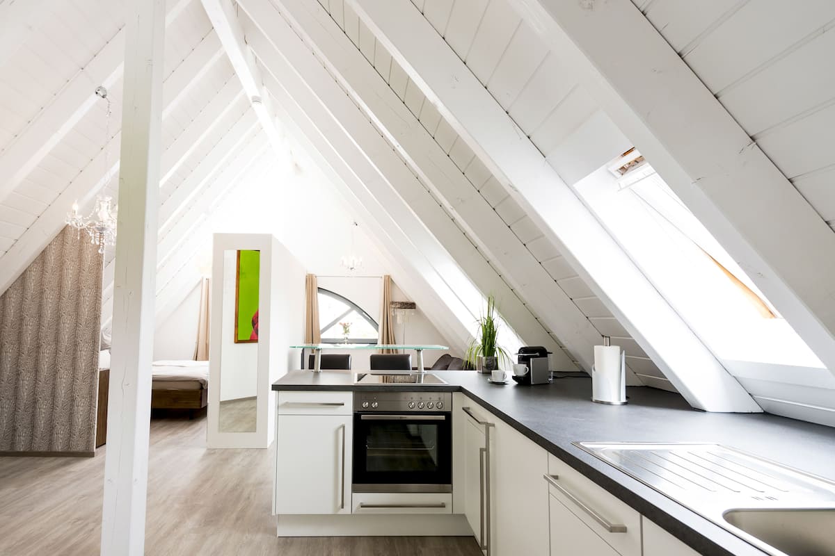 A modern kitchen with a skylight, white cabinetry, and a built-in oven.