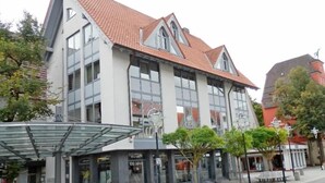 A modern building with large windows and a red-tiled roof. - Postsattler City Apartments (Albstadt)