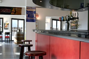 Angolo bar con un impianto di erogazione, sgabelli e un bancone rosso.