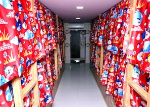 Passadís amb cortines vermelles amb personatges de dibuixos animats, portes de fusta i terra d'rajola.