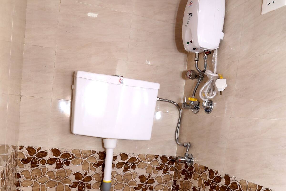 A bathroom with a toilet, a wall-mounted sink, and a showerhead.