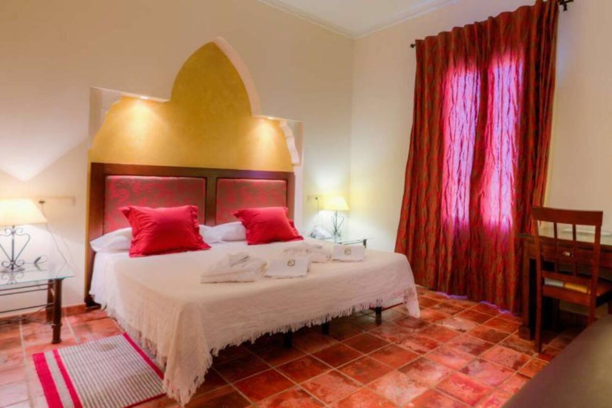Une chambre d’hôtel comprenant un lit, deux tables de chevet avec des lampes, une chaise et un bureau.