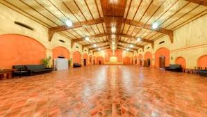 A spacious hall with a high ceiling and arched alcoves, featuring a central stage and seating areas. - Cortijo Los Naranjos de San Juan (Las Cabezas de San Juan)