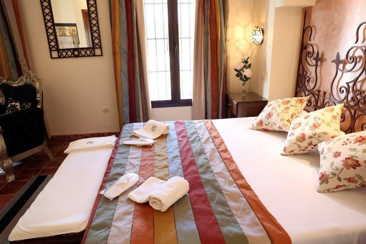 Un lit bien fait, agrémenté d’oreillers à motifs floraux, d’une couverture à rayures et de serviettes posées sur le lit.