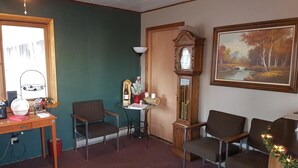 Une pièce chaleureuse avec un bureau en bois, deux chaises, un grand miroir, une horloge à coucou et un tableau encadré.
