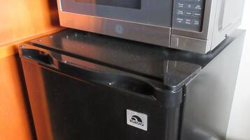 A compact kitchen with a microwave and a refrigerator.