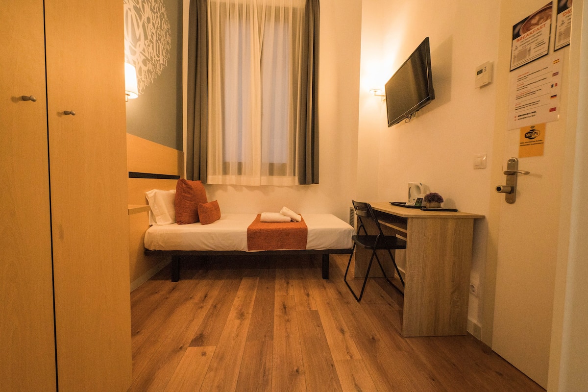 Una habitación pequeña y acogedora con cama, escritorio y televisión.