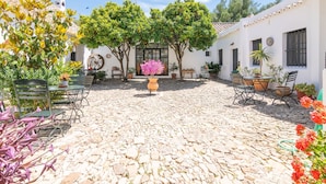 A courtyard with stone flooring, outdoor seating, and potted plants. - Cortijo el Indiviso (Barbate)