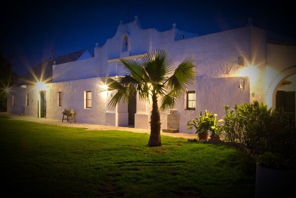 A white building with a palm tree in the foreground, surrounded by a well-maintained lawn. - Cortijo el Indiviso (Barbate)