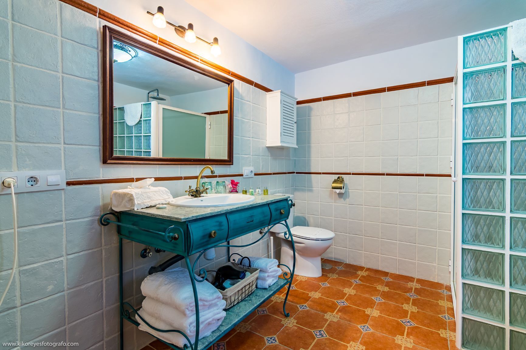 Un baño con lavamanos, espejo e inodoro.
