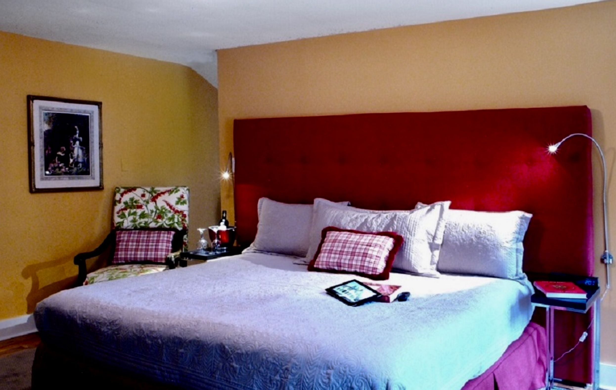 Un dormitorio con una cama grande, cabecera roja y una mesita de noche con lámpara.