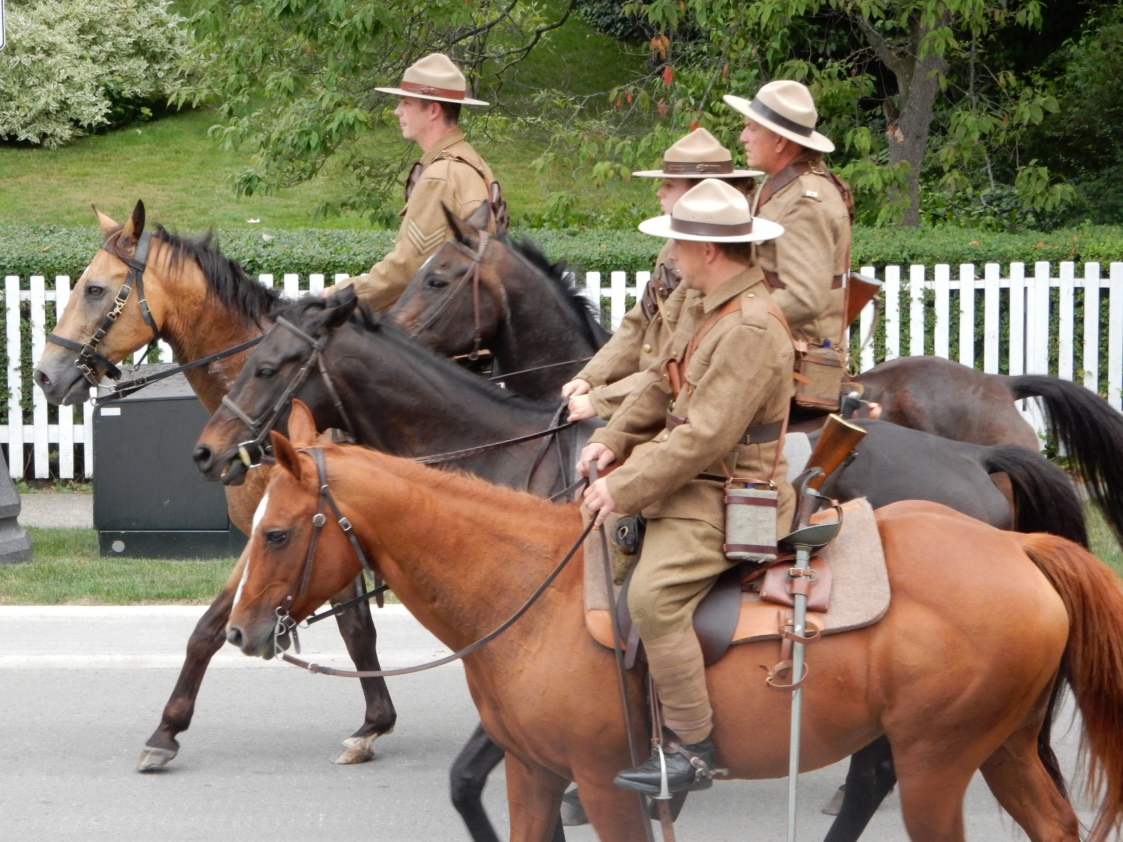 Eine Gruppe von Personen in Uniform reitet auf Pferden auf einer Straße.