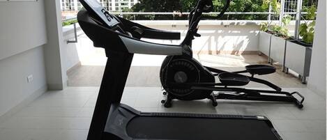 Un gimnasio en casa con una cinta de correr y una máquina elíptica.