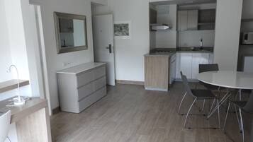 A modern kitchen with a dining area, wooden cabinets, and a white countertop.