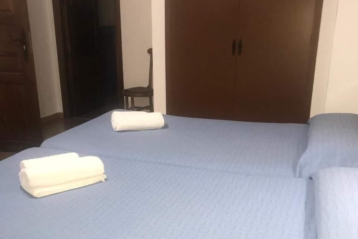 Makuuhuone, jossa on suuri sänky, kaksi tyynyä ja taitettu pyyhe.