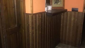 Un comptoir d’accueil en bois, orné d’une affiche encadrée, avec une porte et un sol carrelé.
