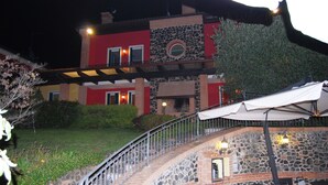A multi-story building with a stone facade, outdoor seating area with umbrellas, and a staircase leading to the entrance. - Tenuta Fortelongo (Fara Vicentino)