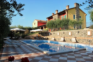 A pool area with a checkered floor, lounge chairs, and a stone building with a tiled pool. - Tenuta Fortelongo (Fara Vicentino)