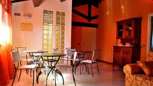 A dining area with a round table and chairs, a cabinet, and a patterned sofa. - Tenuta Fortelongo (Fara Vicentino)