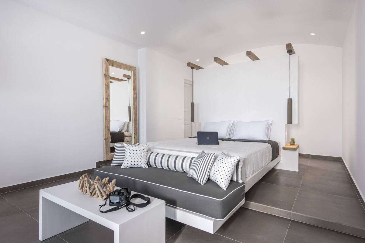 A modern bedroom with a bed, a desk, and a mirror.