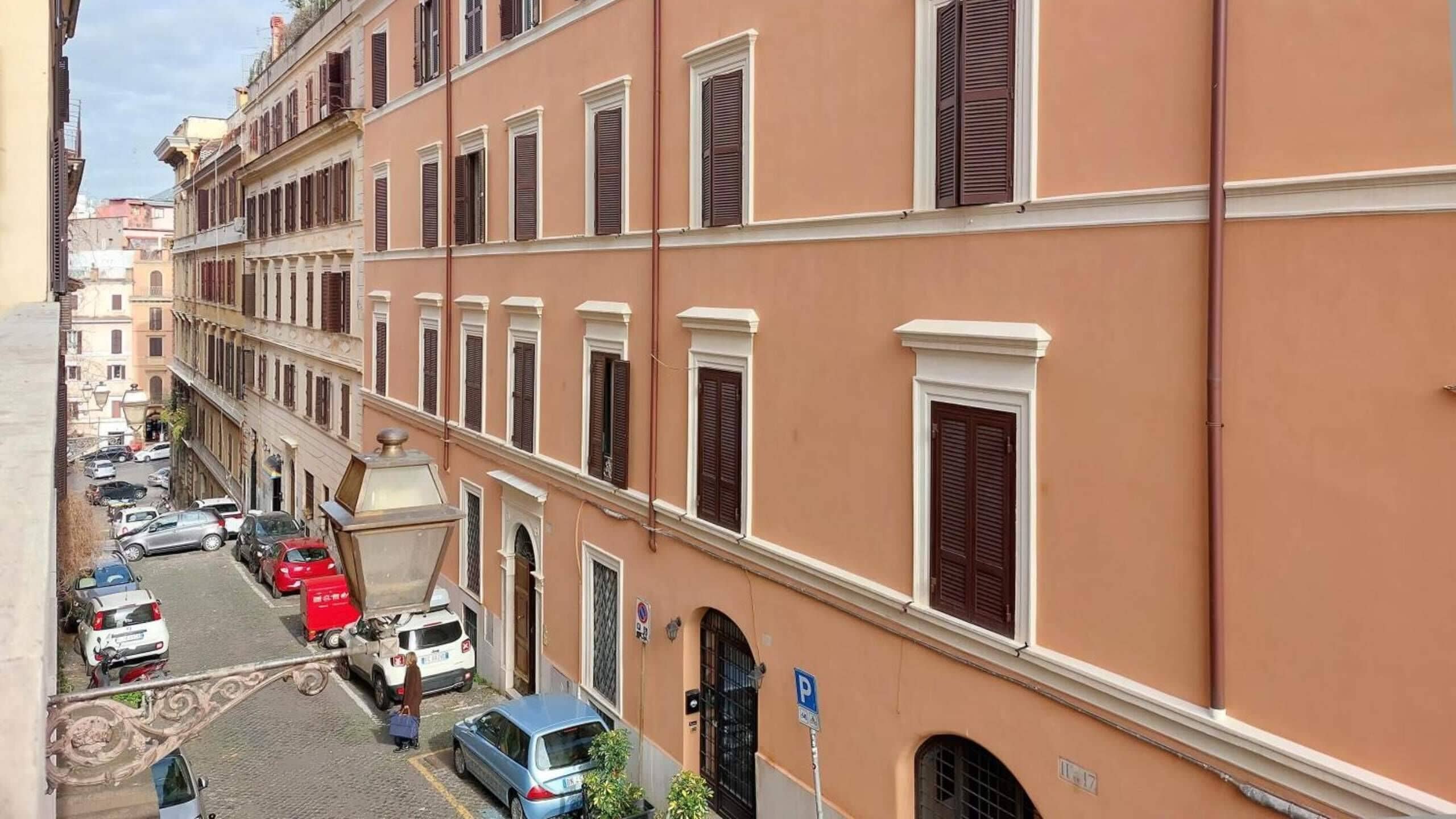 A row of traditional buildings with uniform architectural style, narrow streets, and parked cars.
