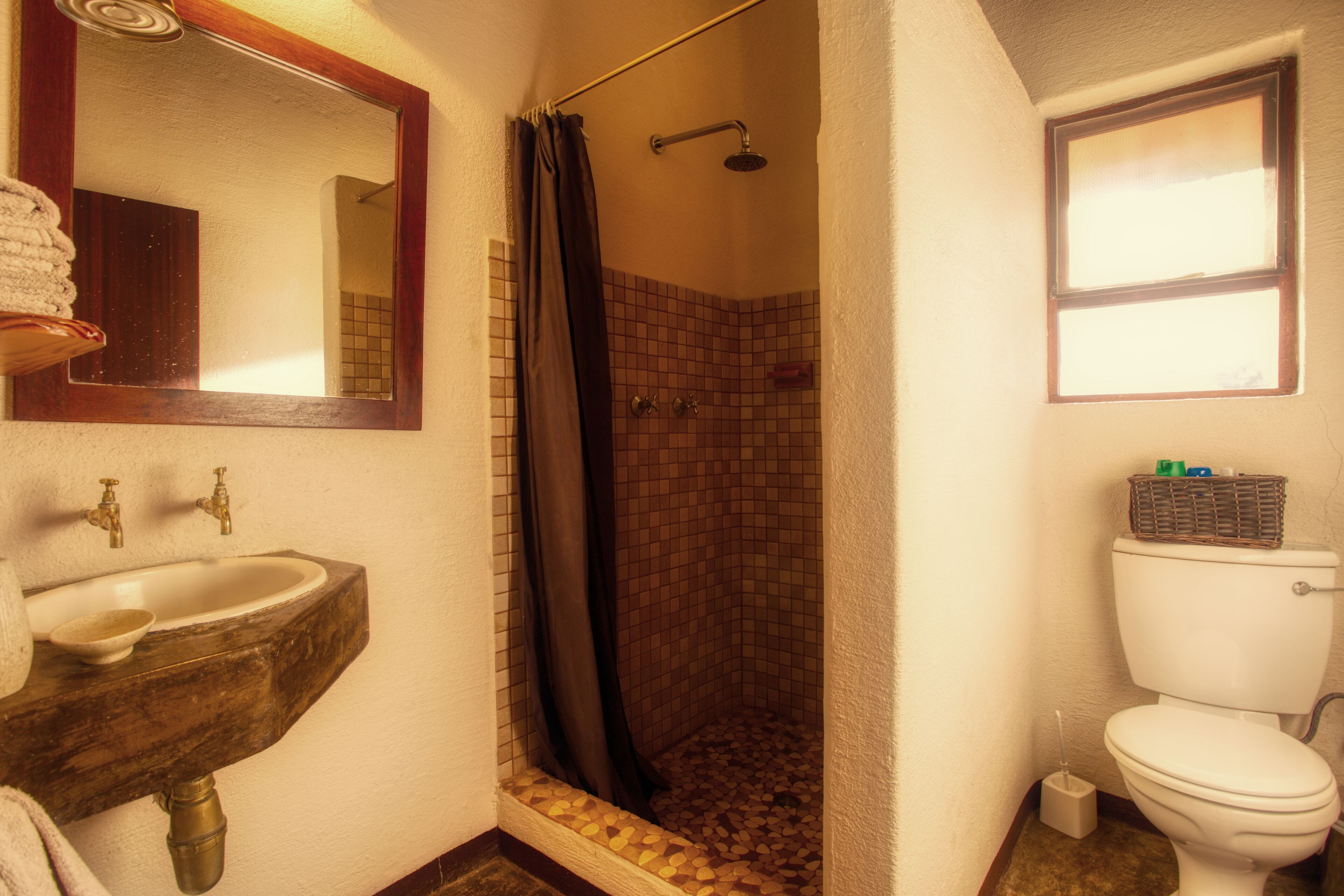 A bathroom with a sink, mirror, shower, and toilet.