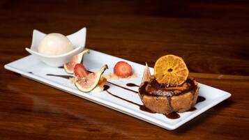 A dessert plate with a chocolate cake topped with an orange slice, figs, and a scoop of ice cream.