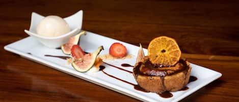 A dessert plate with a chocolate cake topped with an orange slice, figs, and a scoop of ice cream.