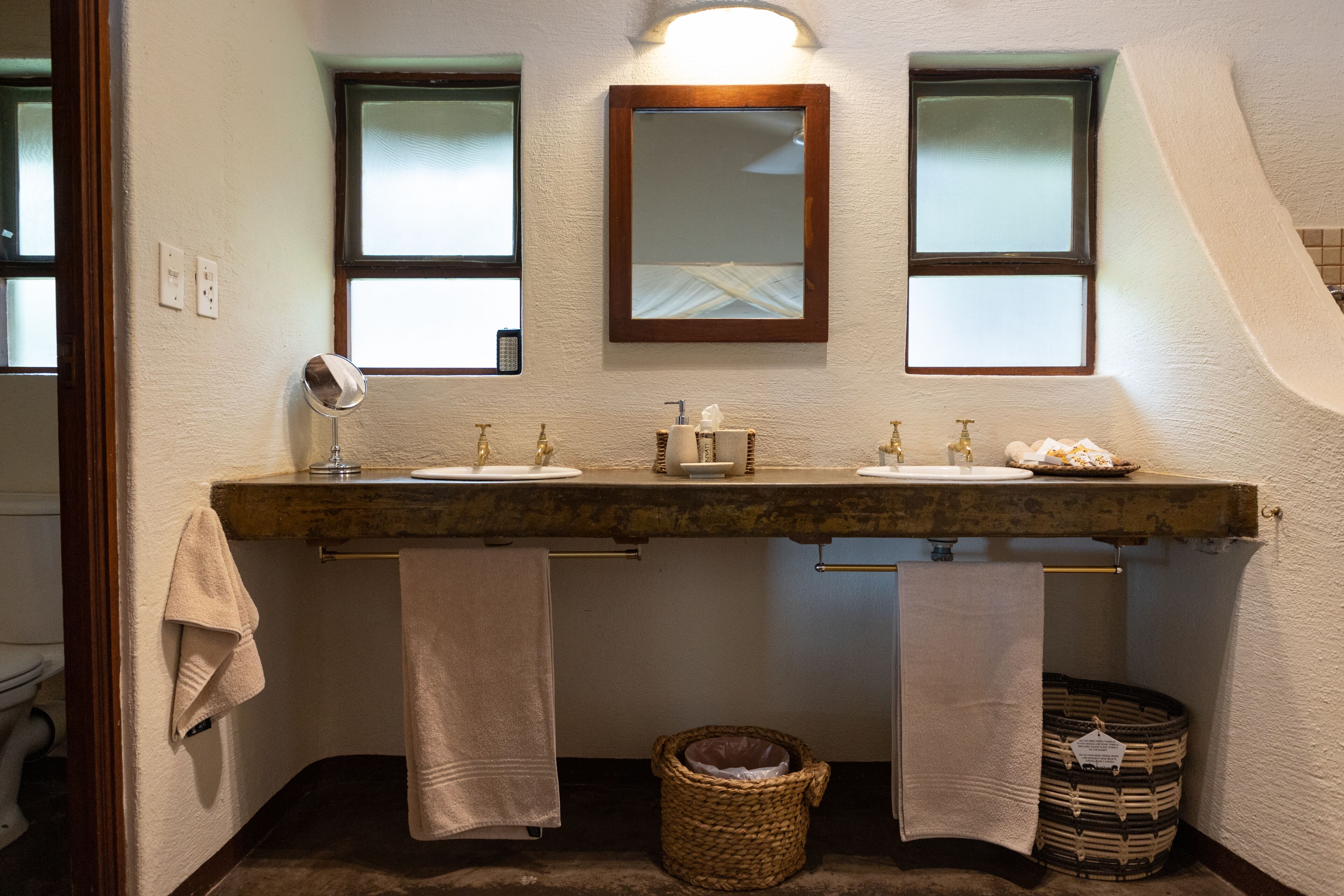 A bathroom with a double sink, two mirrors, and a towel rack.